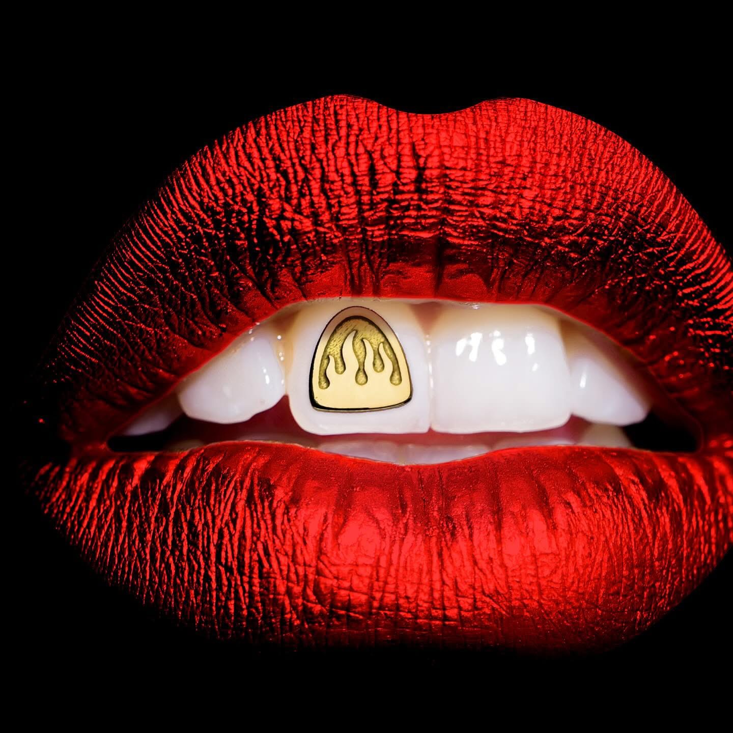 Mosuth with vibrant red lipstick showing off a tooth gem